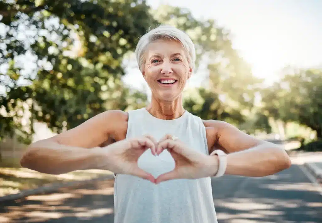 Happy Older Woman Outdoors Making a Heart Gesture With Her Hands