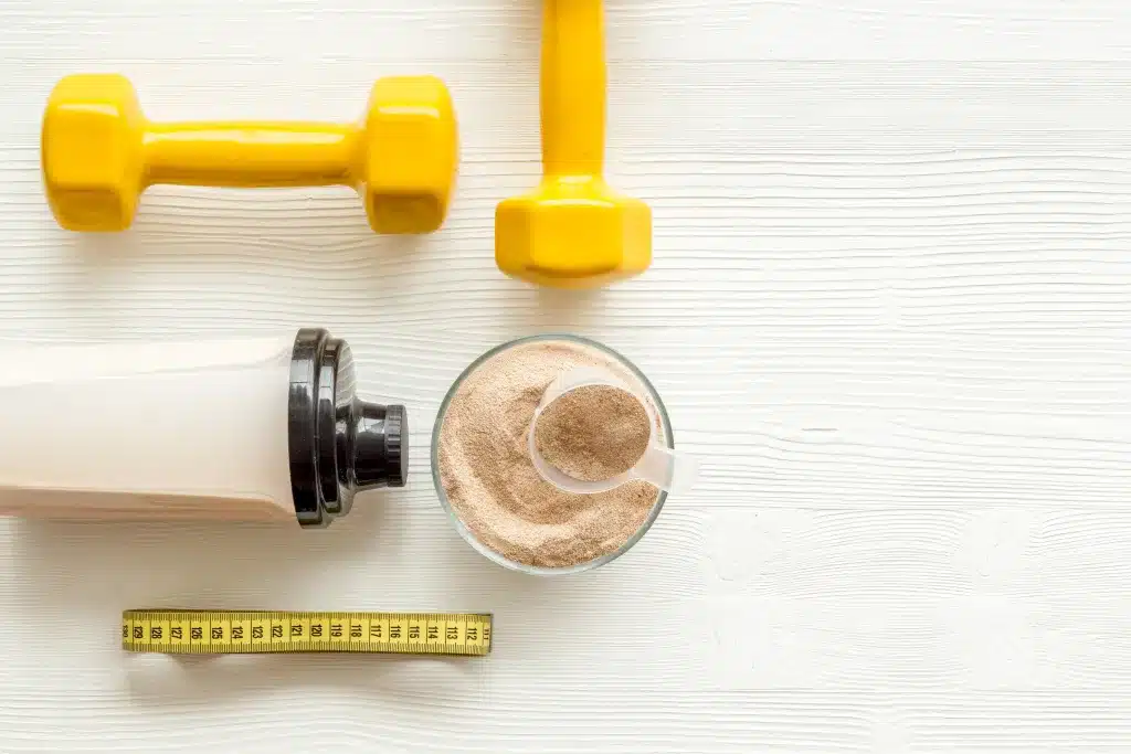 Meal Replacement Shake Powder Beside Yellow Dumbbells