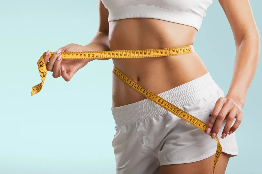 Woman Using Yellow Tape Measure to Measure Stomach