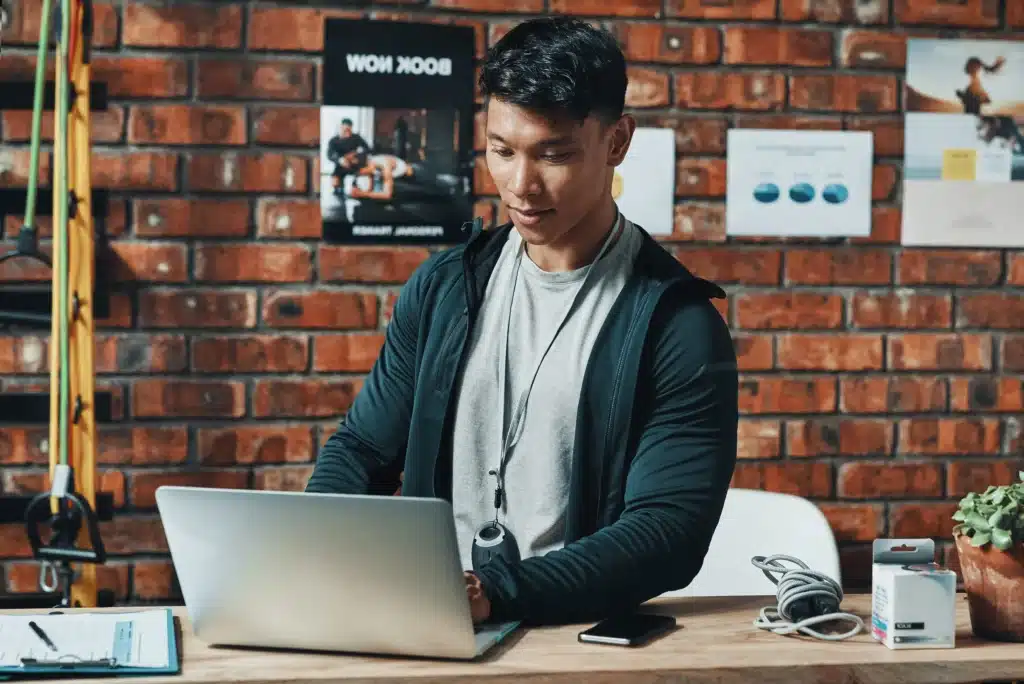 Image of Personal Trainer Sat at a Desk on his Laptop in an Office
