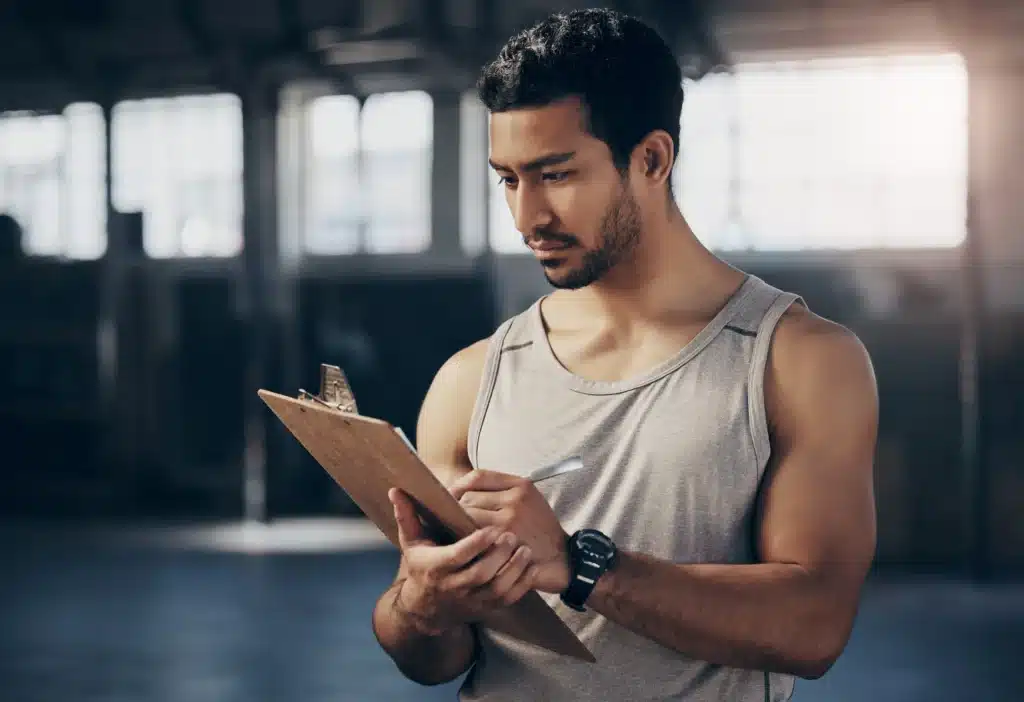 Image of a Male Personal Training Writing on a Wooden Clipboard