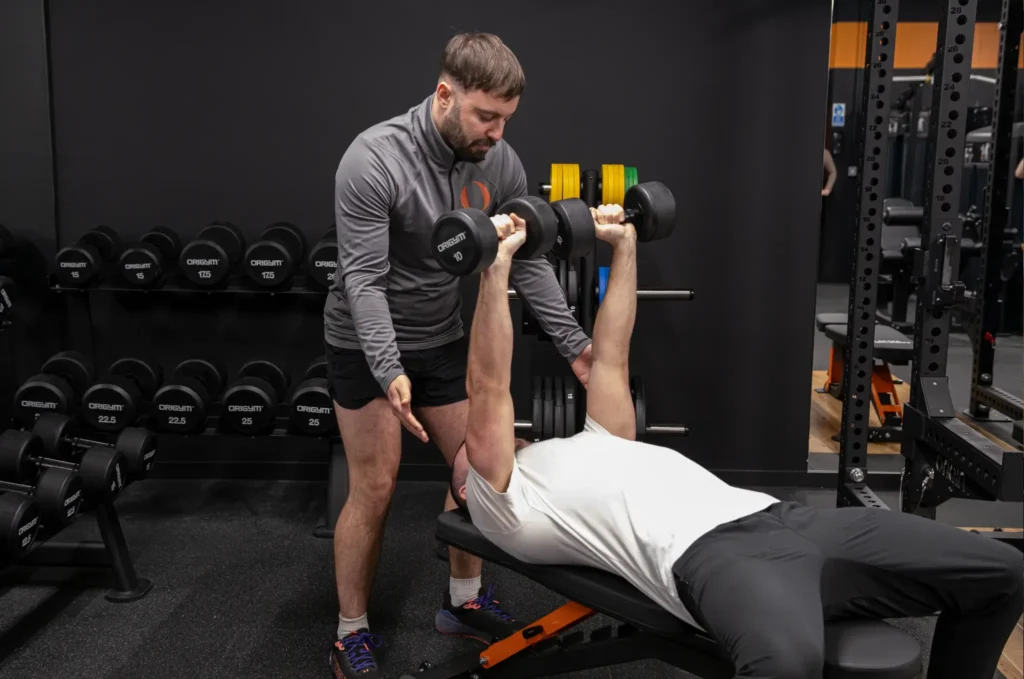 Image of an OriGym Personal Trainer in the Gym Coaching a Client Using Weights